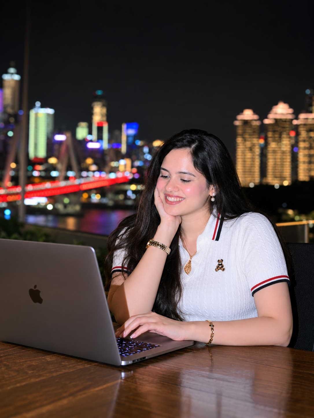 Shruti Mishra working on a laptop with a night cityscape behind her
